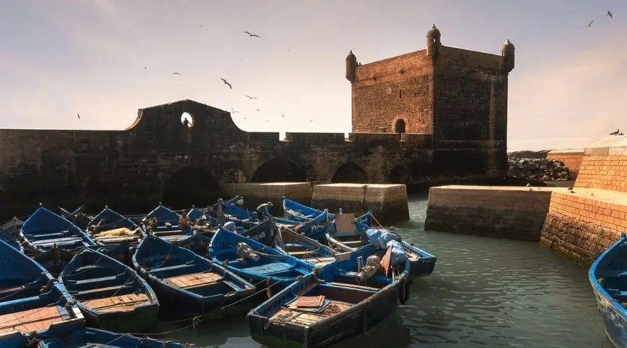 Essaouira Morocco travel guide: blue fishing boats in the port below the old sea fort