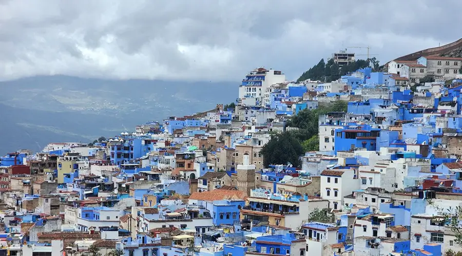 Morocco blue city Chefchaouen at dusk, its blue houses spread below the Rif Mountains